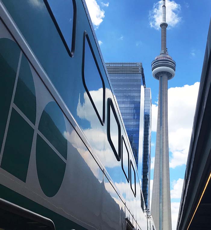 GO Train arriving in downtown Toronto with view of CN Tower.